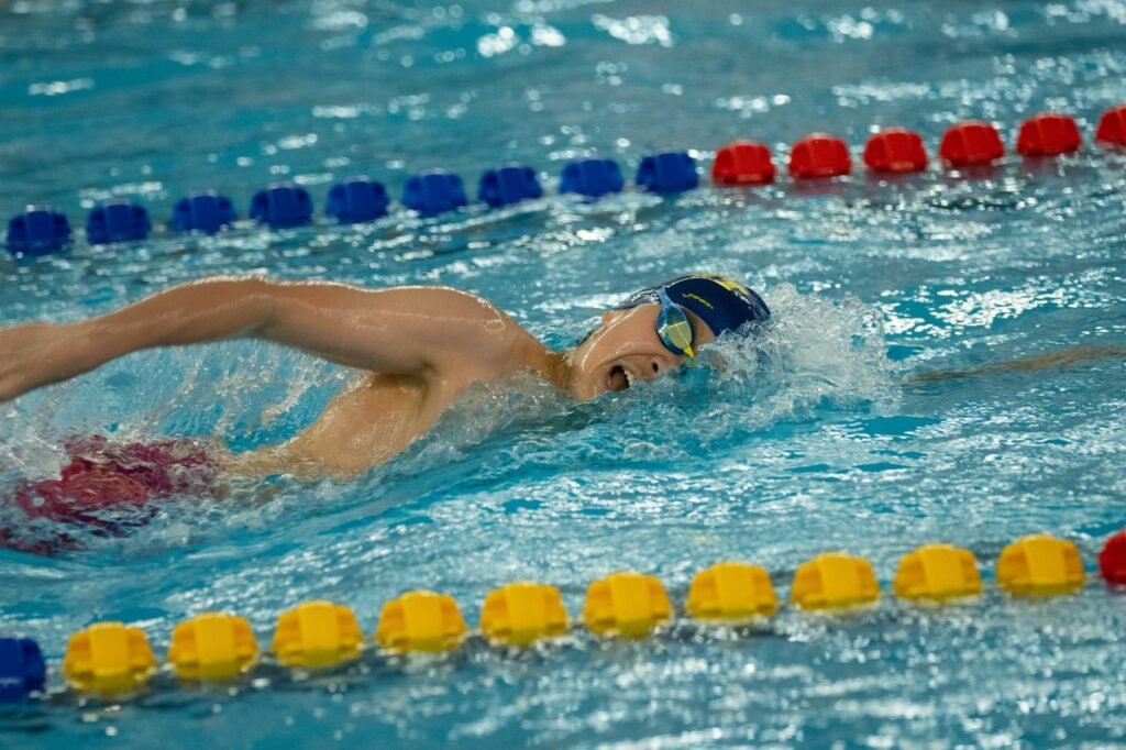 Swimmer performing freestyle stroke in an indoor pool during competition.
